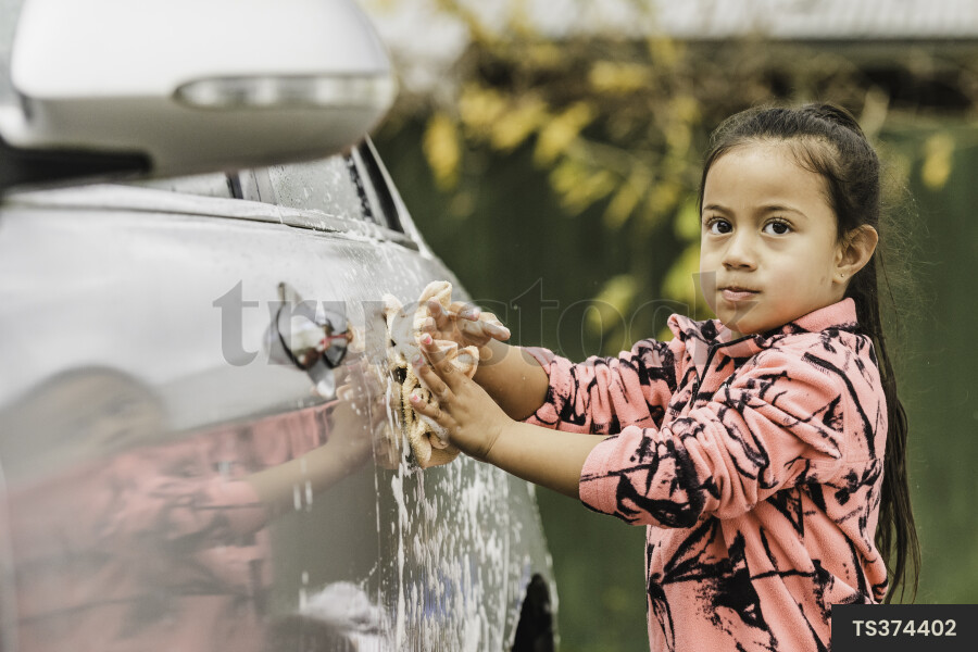 Maori girl washing car at home