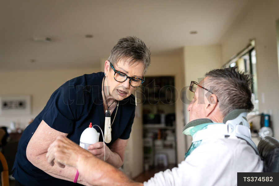 Health carer giving medicine to patient with neck brace