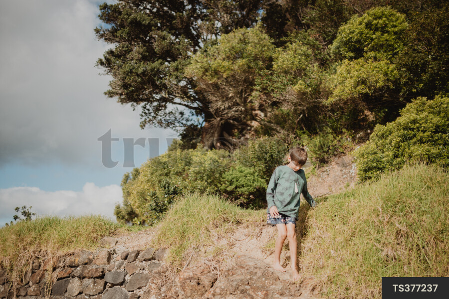 Barefoot boy walking on rocky coastline
