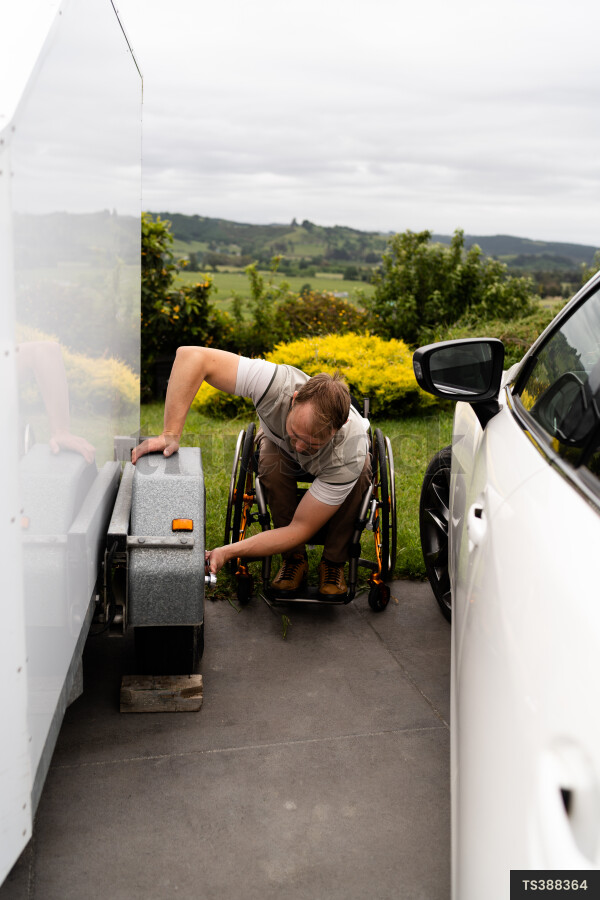 Man in wheelchair changing tyre on trailer