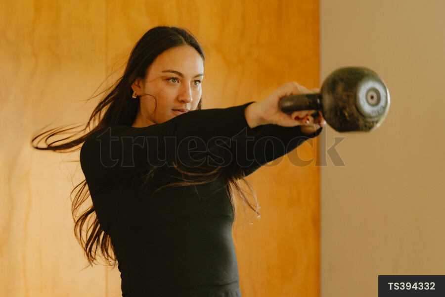 Female personal trainer weight training with dumbbell