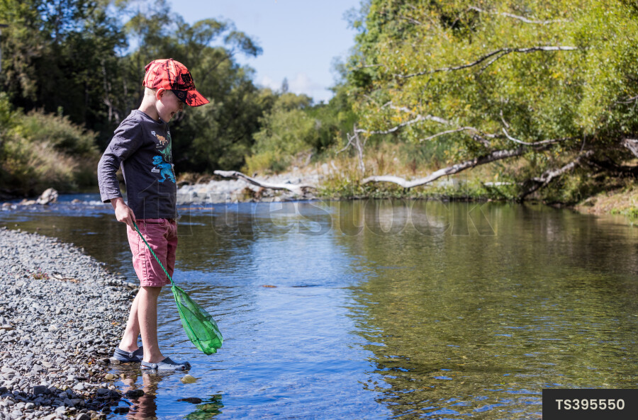 Boy with fishing net by river
