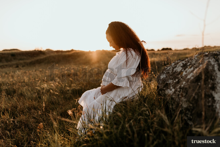 Woman Sitting in Field for Maternity Shoot