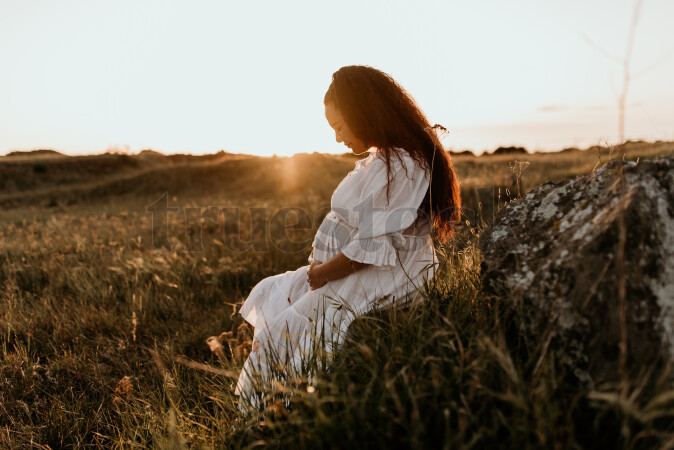 Woman Sitting in Field for Maternity Shoot