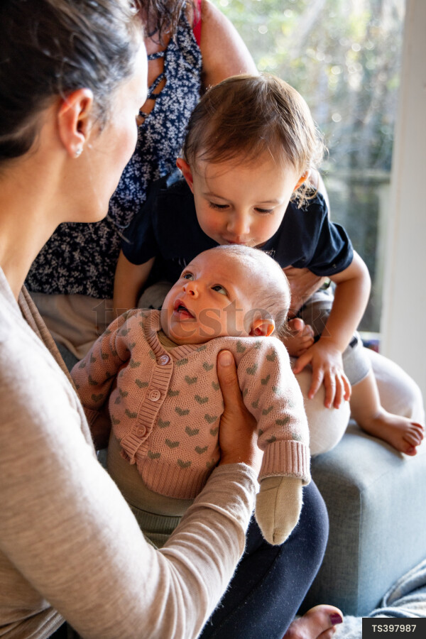 Brother kissing sister on sofa with family in living room