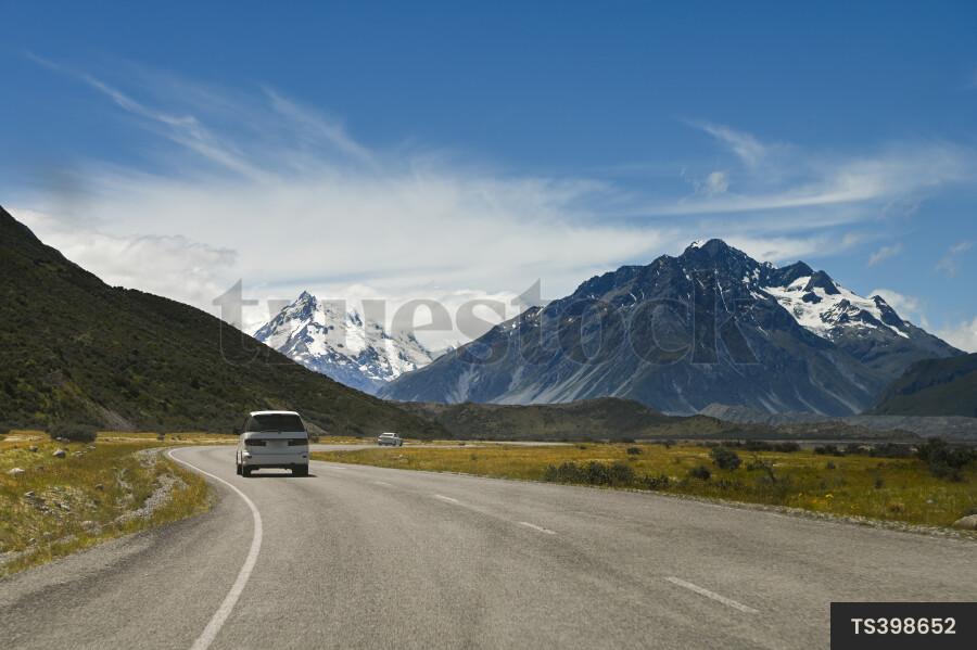Cars on road trip next to mountain with snow