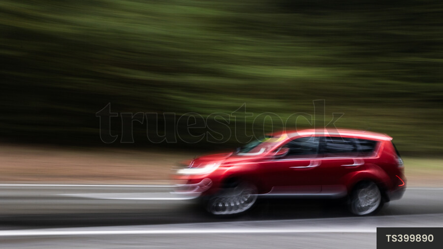 Long exposure of red car driving on road