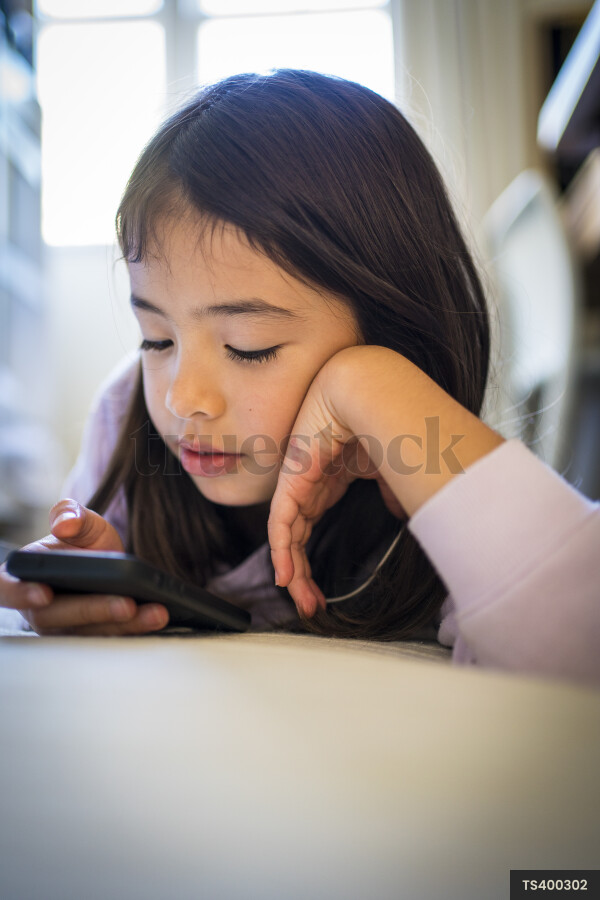 Girl listening to music on headphones in bedroom
