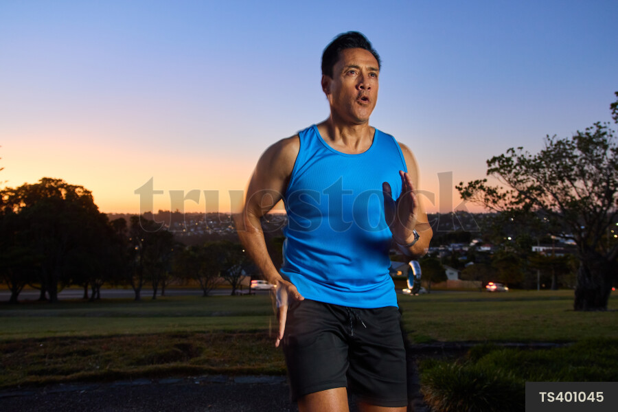 Man running on sidewalk in park during sunset
