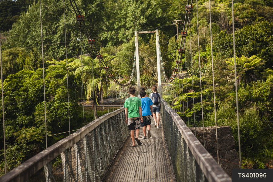 Teenagers hiking across bridge in Karangahake Gorge