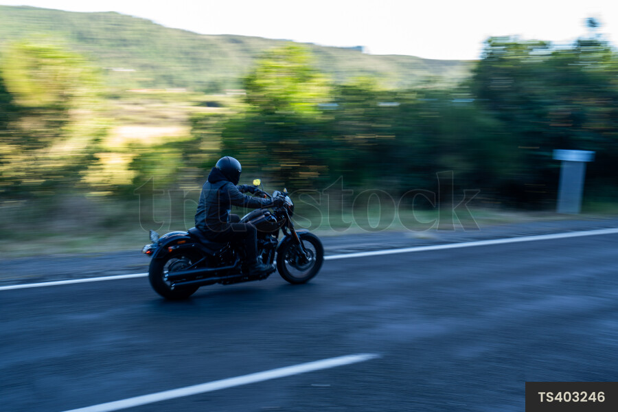 Man riding motorbike on road by mountain