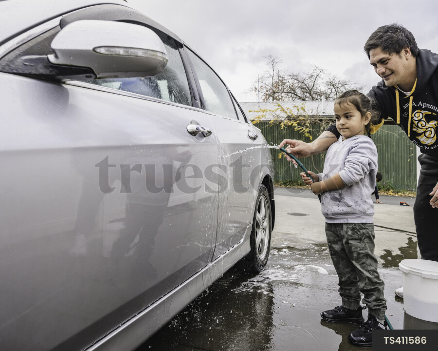 Father and daughter washing car at home