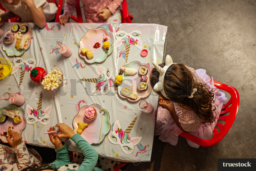 Children sitting at the table eating food at a birthday party