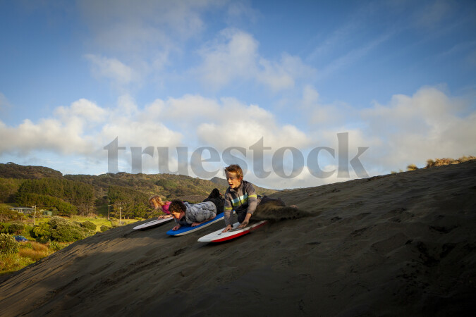 Kids on Boogie Board Down Sand Bank