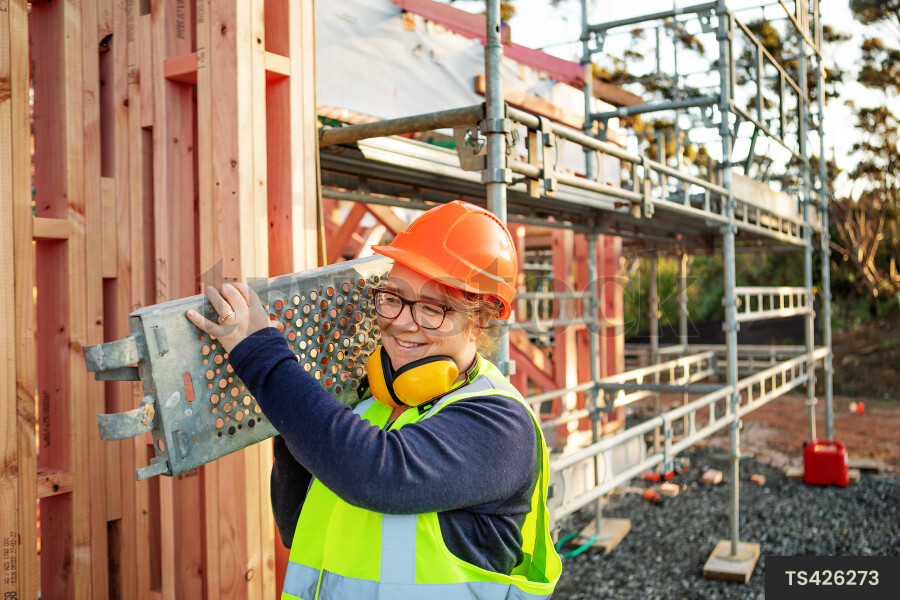 Woman carrying scaffolding in construction site