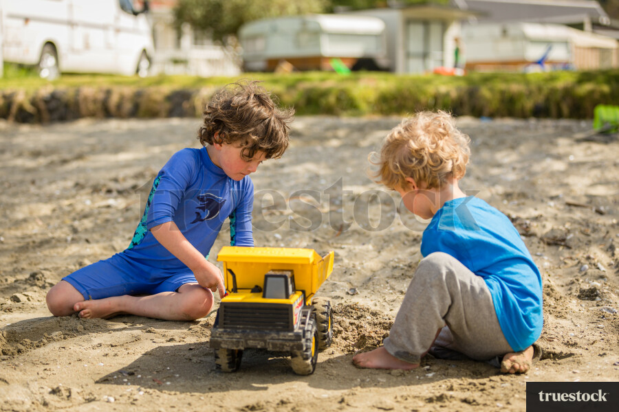 Children playing with toy truck in the sand