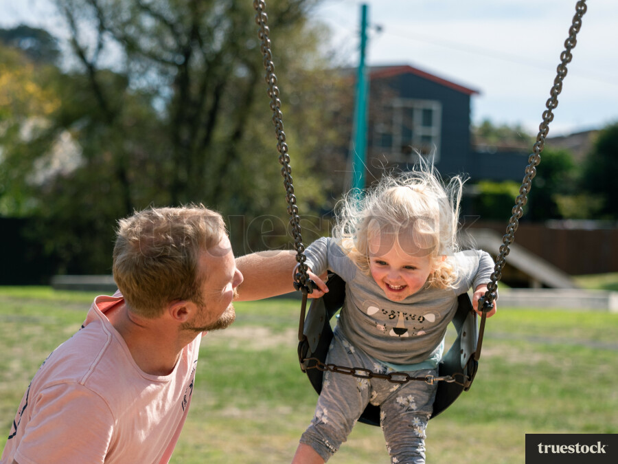 Father pushing daughter in the swing