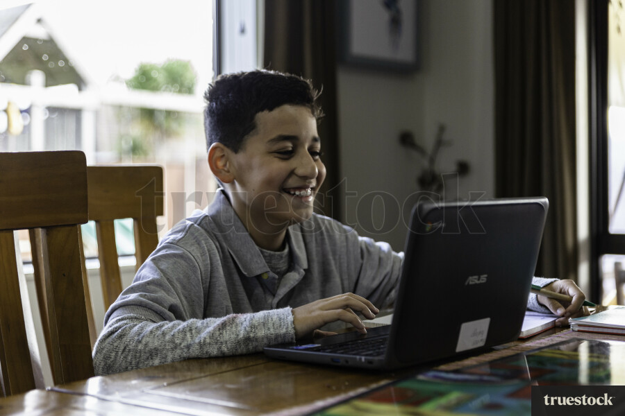 Boy sitting at Table using a Laptop
