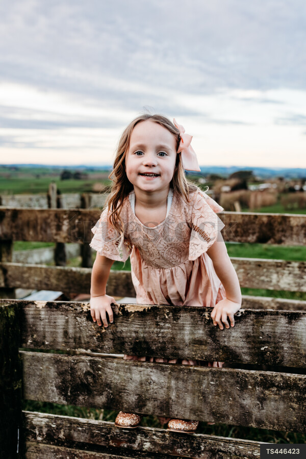 Portrait of girl climbing on fence of paddock