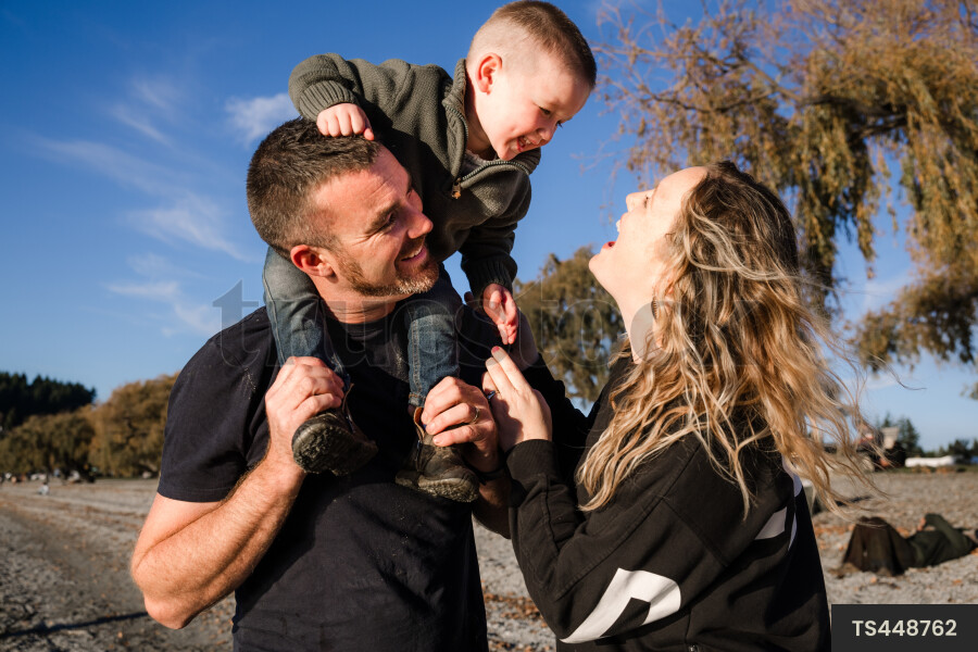Happy couple carrying son on shoulders