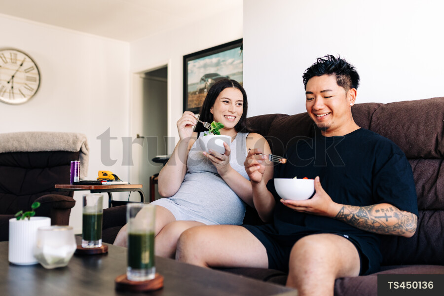 Couple eating salad on sofa