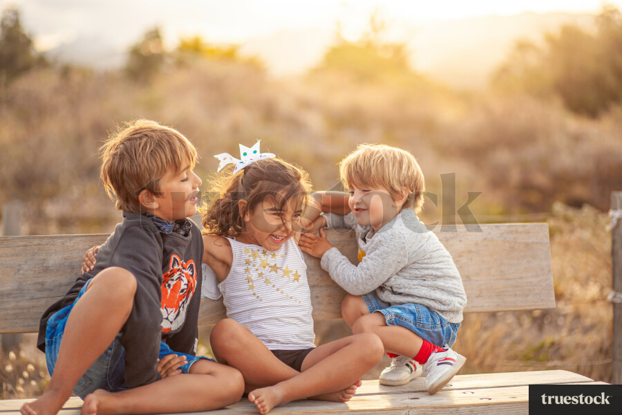 Siblings sitting on picnic bench at the beach together and hugging