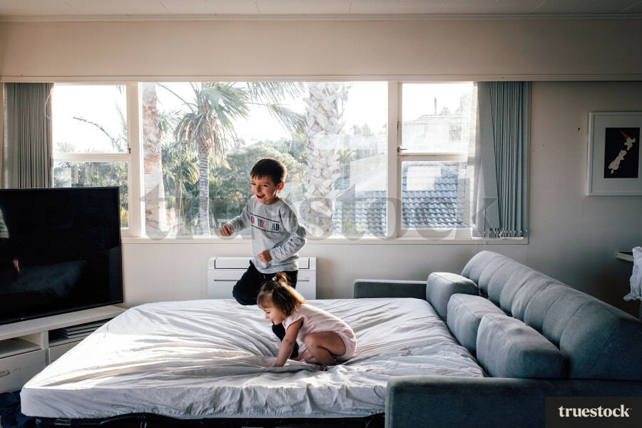 Young Boy and Girl Jumping on Bed