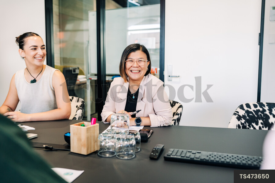 Businesspeople smiling during meeting in boardroom