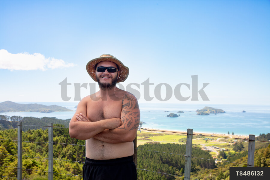 Portrait of shirtless Maori man by fence on coastline