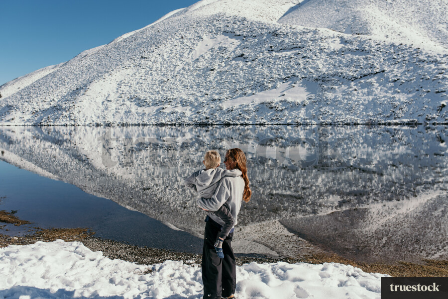 Mum Holding Child in front of Snowy Landscape