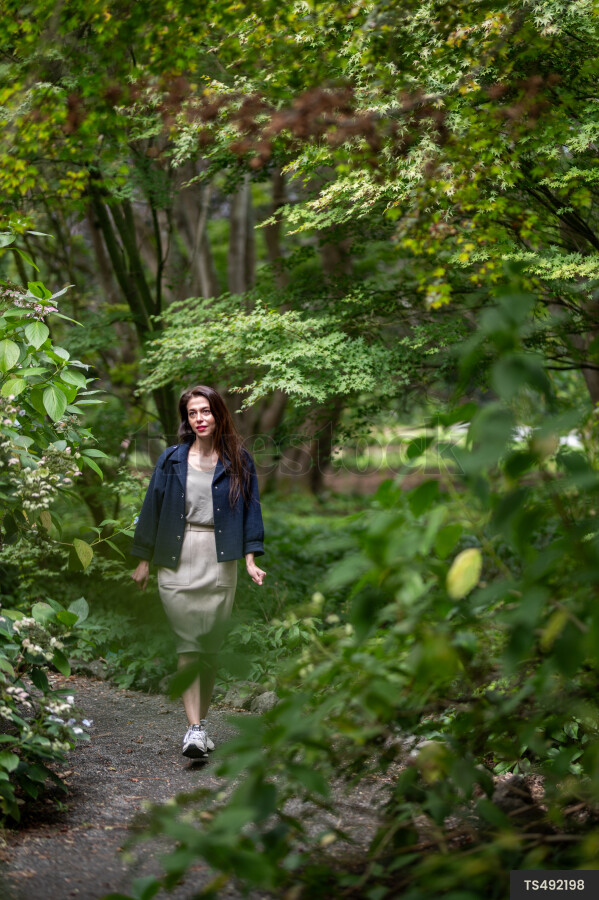 Woman with blue jacket walking in park