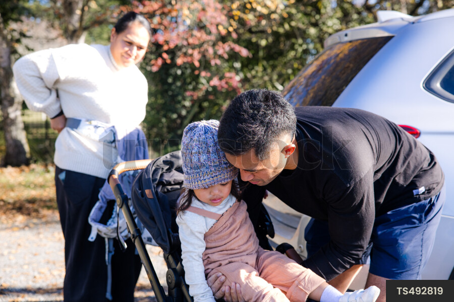 Young family with baby buggy by car