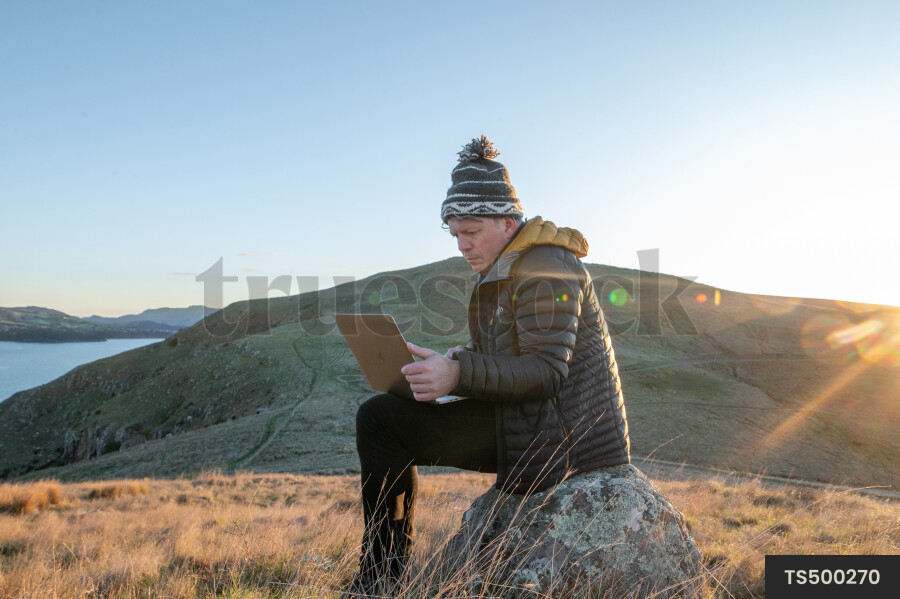 Man with laptop on rock