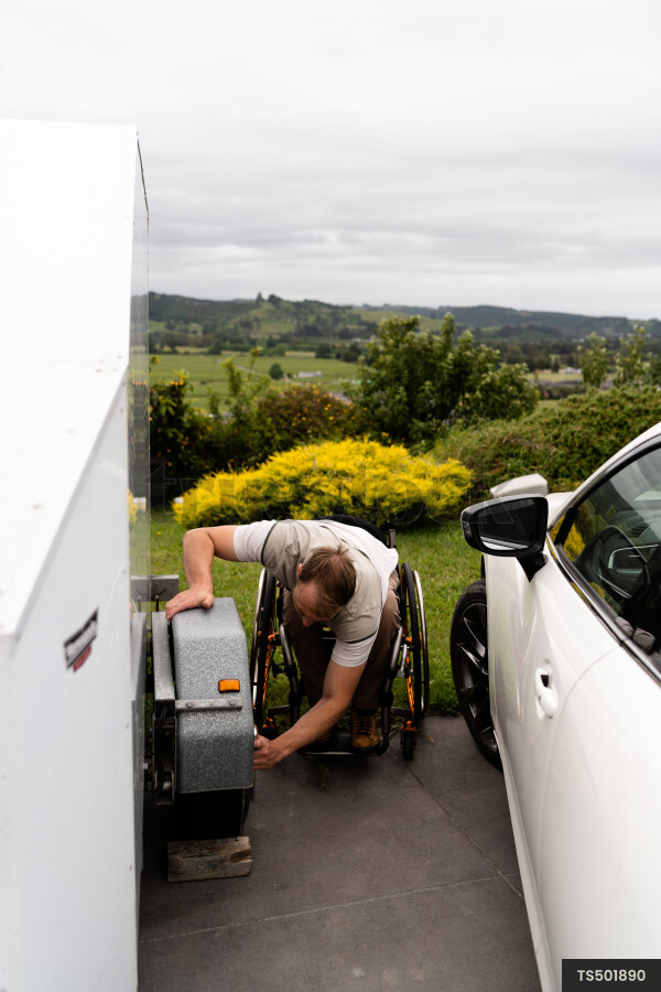 Man in wheelchair changing tyre on trailer