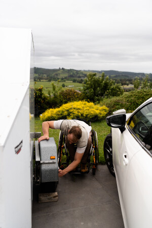 Man in wheelchair changing tyre on trailer