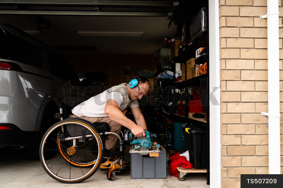 Man in wheelchair doing DIY in garage