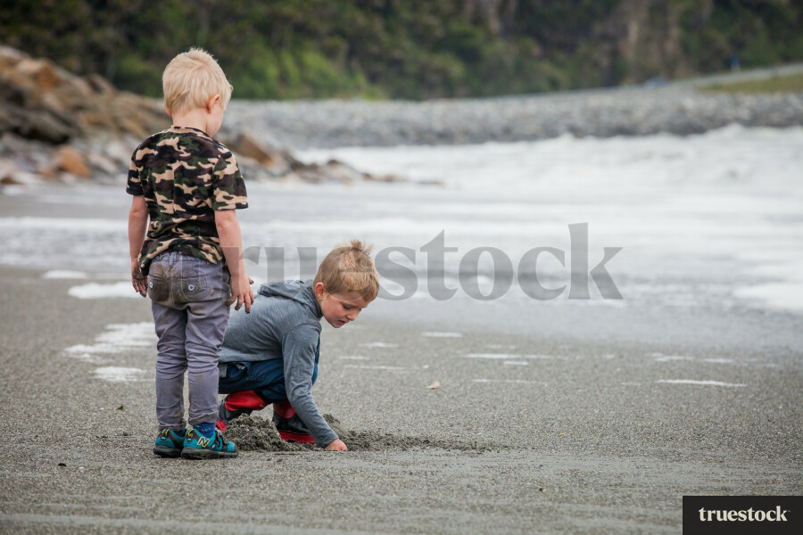 Children digging holes in the sand at the beach