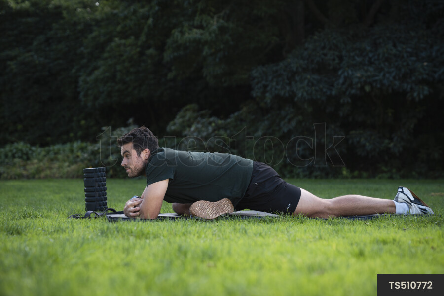 Man stretching on exercise mat in park