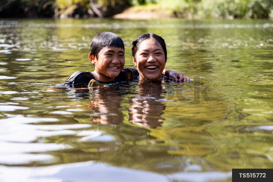 Smiling boy and girl swimming in river