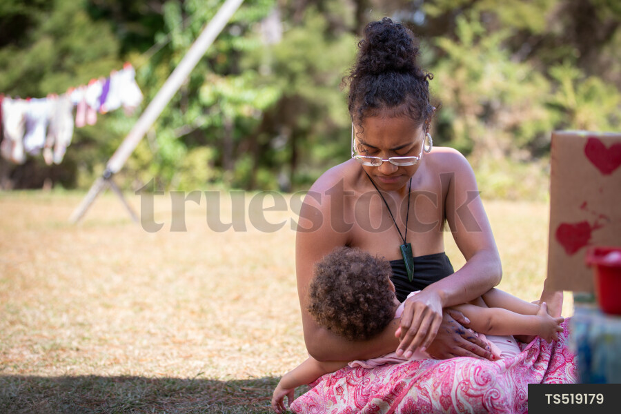 Mother breastfeeding daughter outside in garden