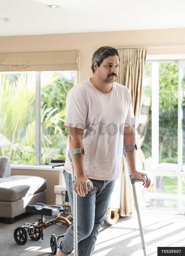 Disabled man with crutches in house