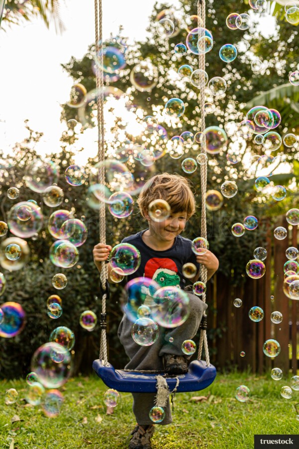 Child on the swing playing with bubbles