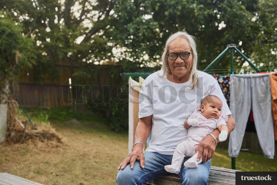 Grandfather Holding Granddaughter in Backyard