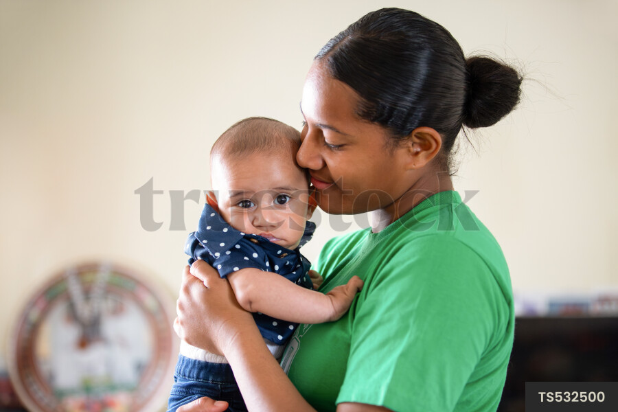 Tongan sister holding baby brother in room