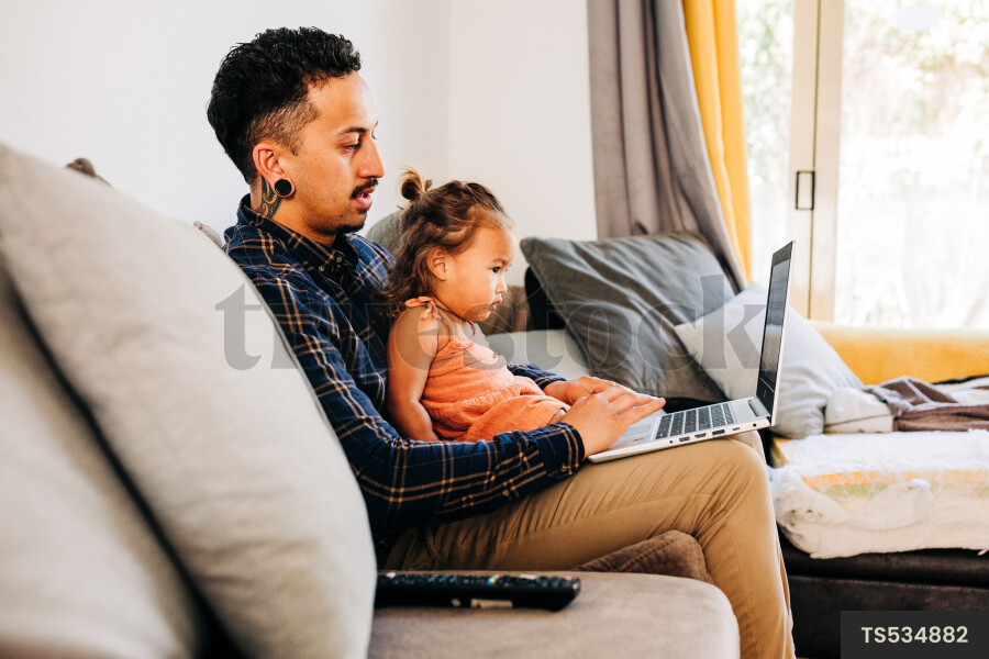 Māori father with kid working on laptop