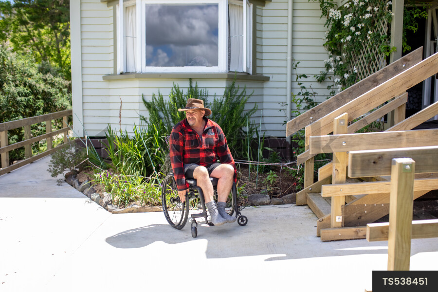 Man in Wheelchair Out front of House