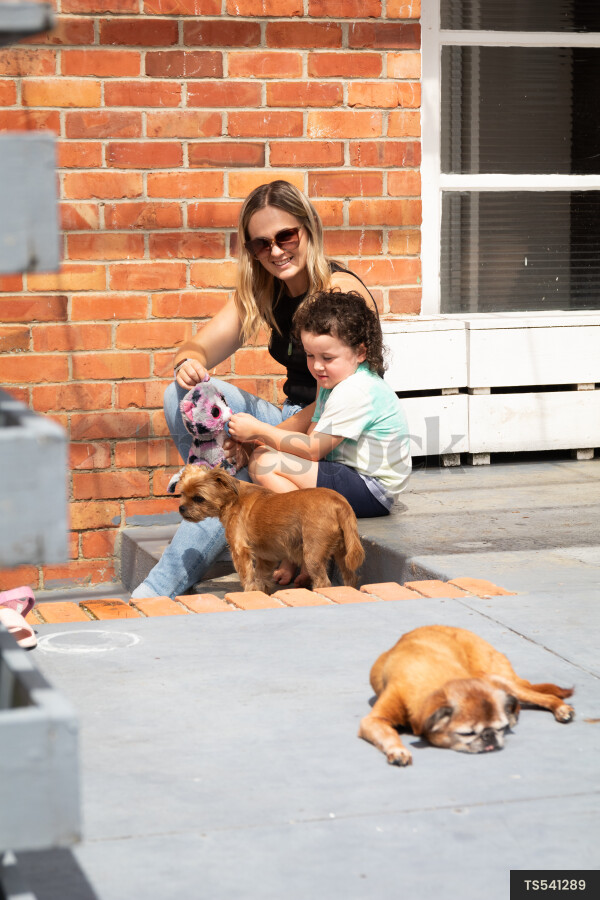 Woman and daughter sitting on patio with dogs