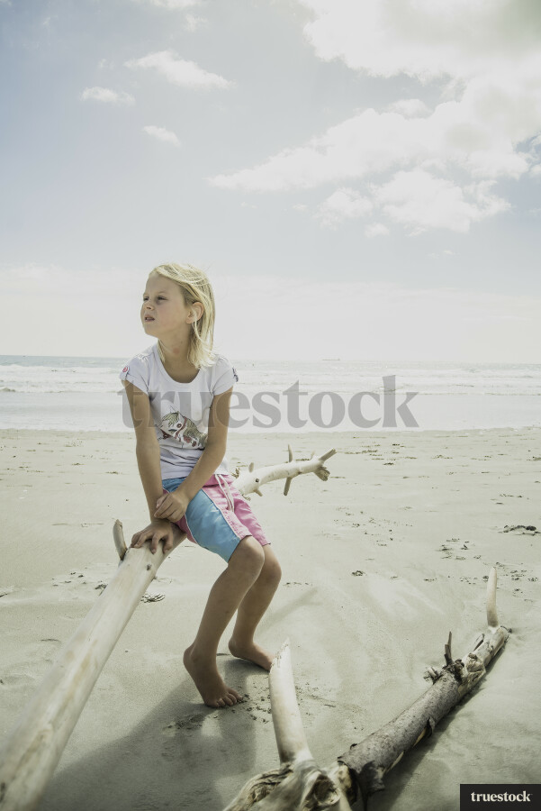 Young Girl Sitting on Wood at Beach