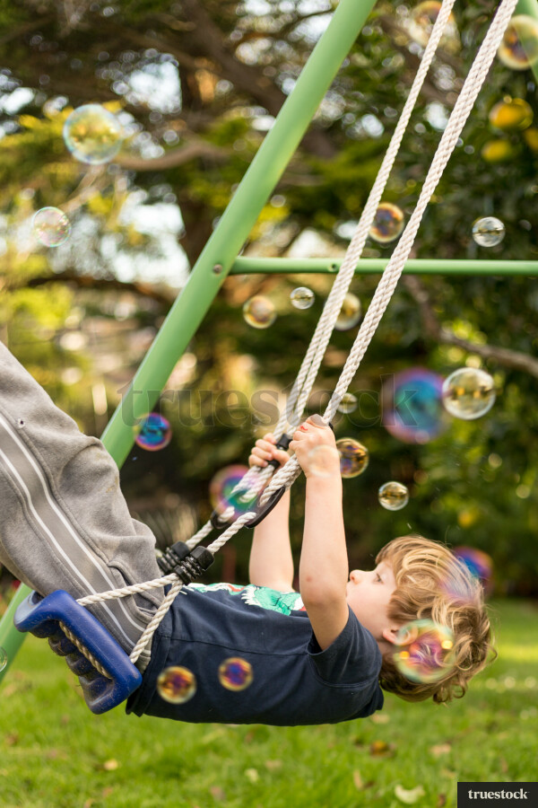 Child on the swing playing with bubbles