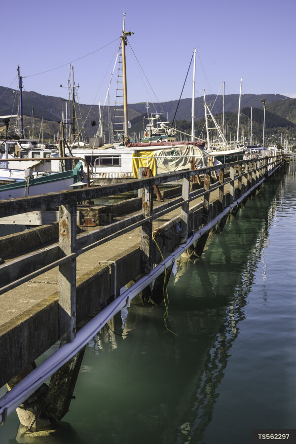 Boats in sea next to bridge in harbour by mountain
